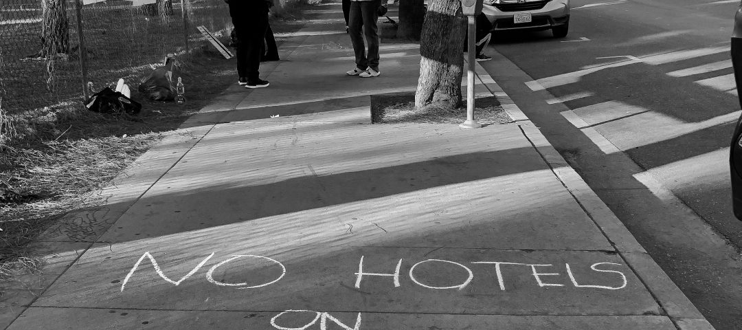 "no hotels on public land" written in sidewalk chalk black and white photograph